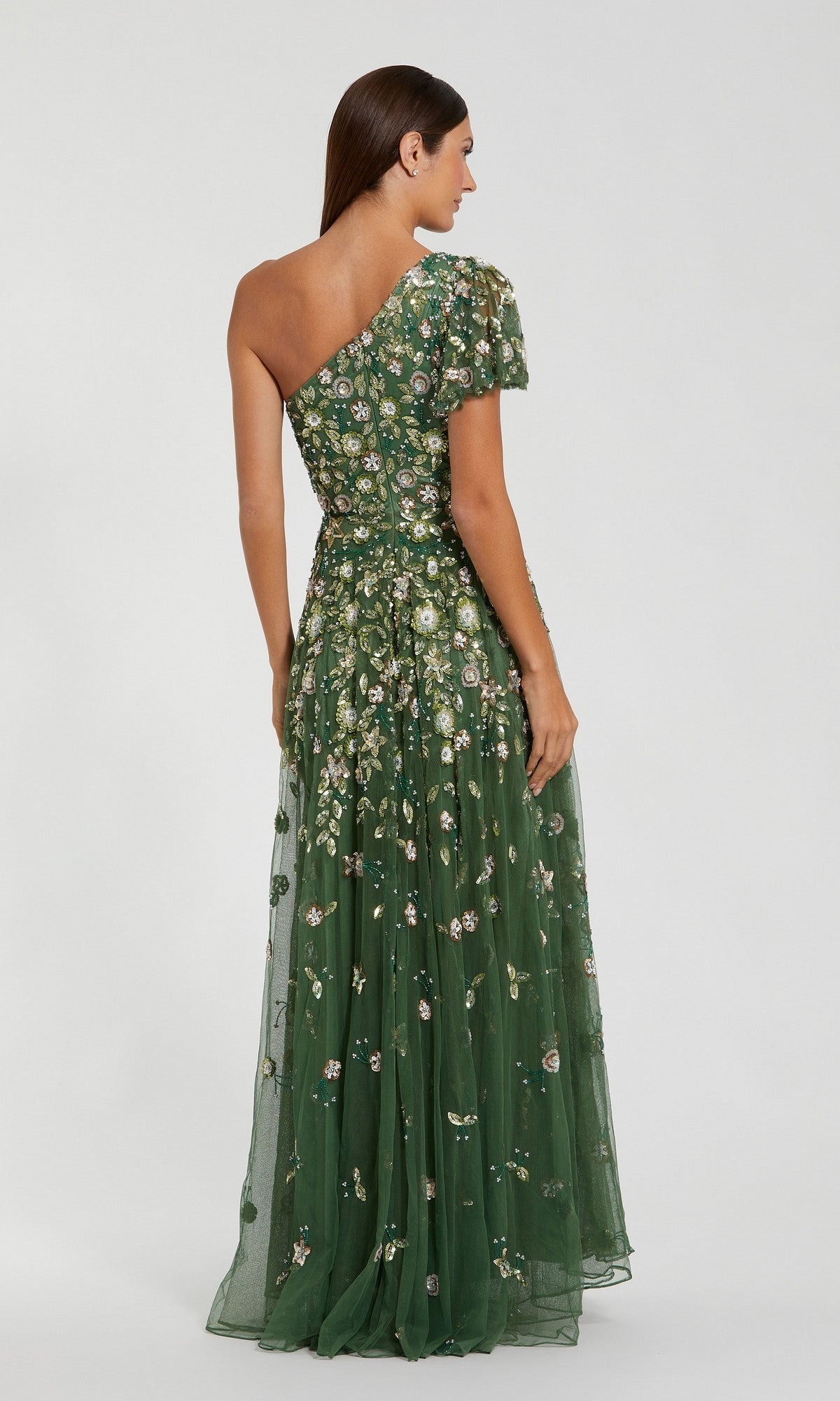 Model wears the Mac Duggal 6159 long formal dress in sage green, featuring one-shoulder styling and exquisite floral embellishments, shown from the back against a plain background.